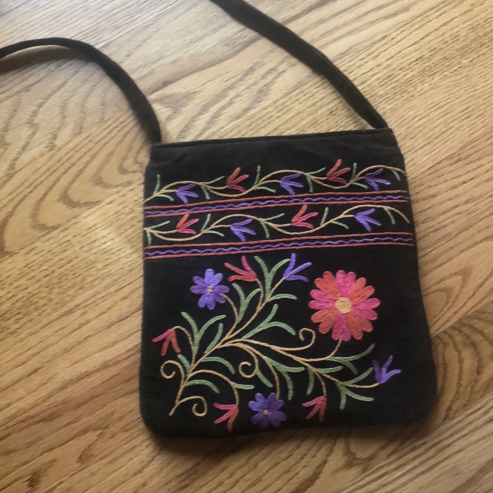 Crossbody purse with flower design on brown suede.